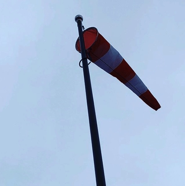 Randig vindstrut i oranget och vitt på en flaggstång